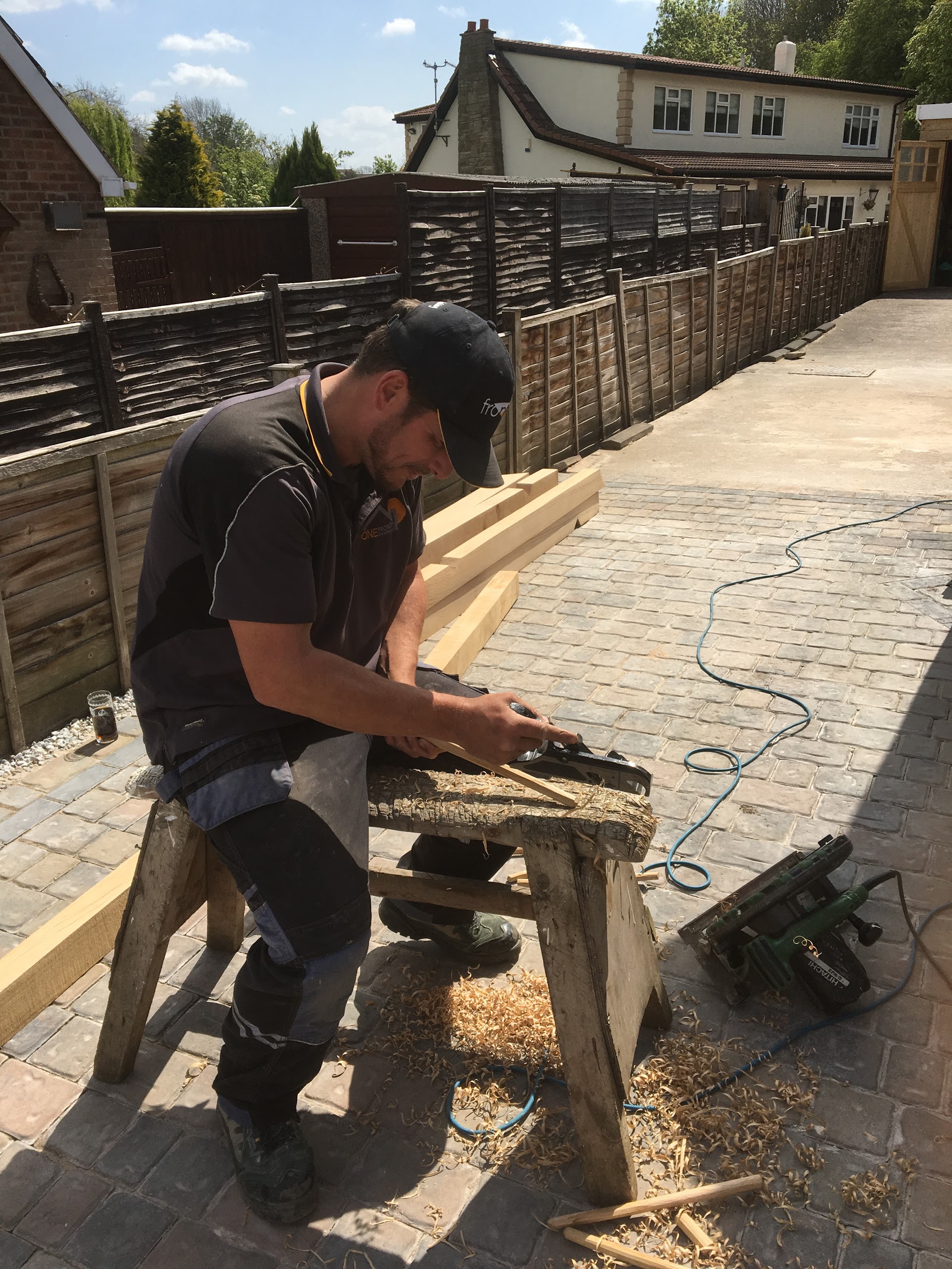 Craftsman shaping timber by hand on a sawhorse for an onsite gate